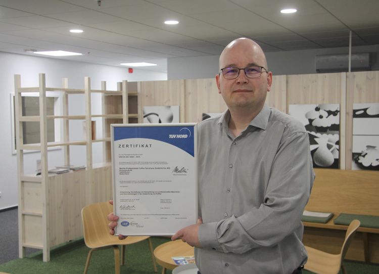 Tony Fischer, Umweltmanagement-Beauftragter bei Melitta Professional, präsentiert das Zertifikat des TÜV Nord